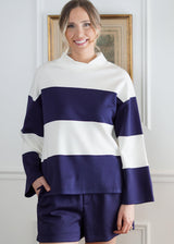 Woman wearing a navy and white striped sweater with shorts indoors.